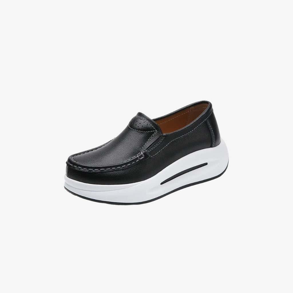Damesloafers van zwart synthetisch leer, met een dikke witte zool voor een moderne en comfortabele stijl. Het minimalistische ontwerp heeft zichtbare stiksels en een makkelijke instap, perfect voor een look die elegant en ontspannen tegelijk is.