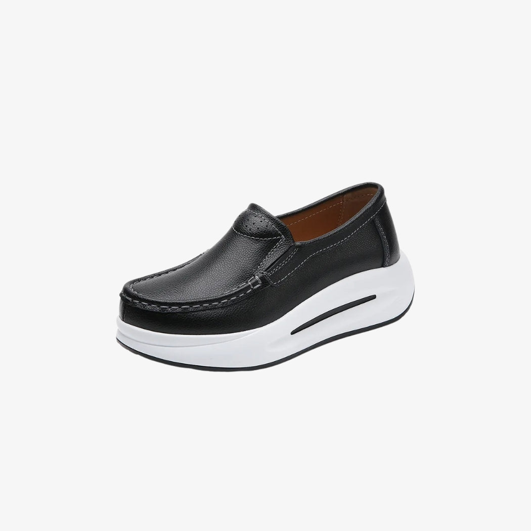 Damesloafers van zwart synthetisch leer, met een dikke witte zool voor een moderne en comfortabele stijl. Het minimalistische ontwerp heeft zichtbare stiksels en een makkelijke instap, perfect voor een look die elegant en ontspannen tegelijk is.