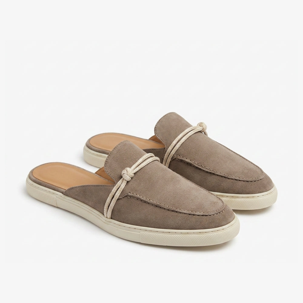 Loafer muiltjes van echt suèdeleer in bruin en taupe, met een beige zool en bandje, op een grijze achtergrond