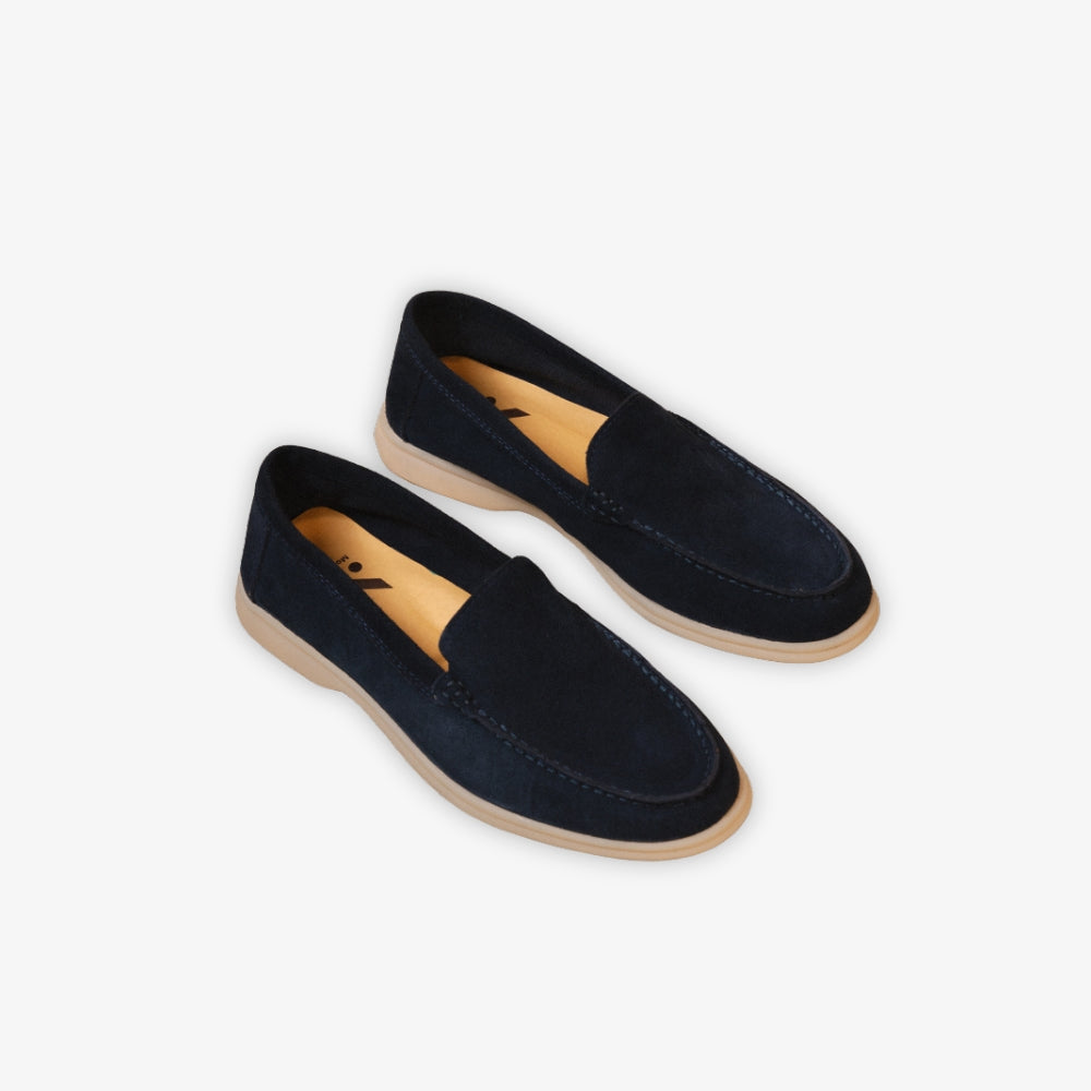 blauwe bootschoen-loafer op de grond, tegen een beige achtergrond