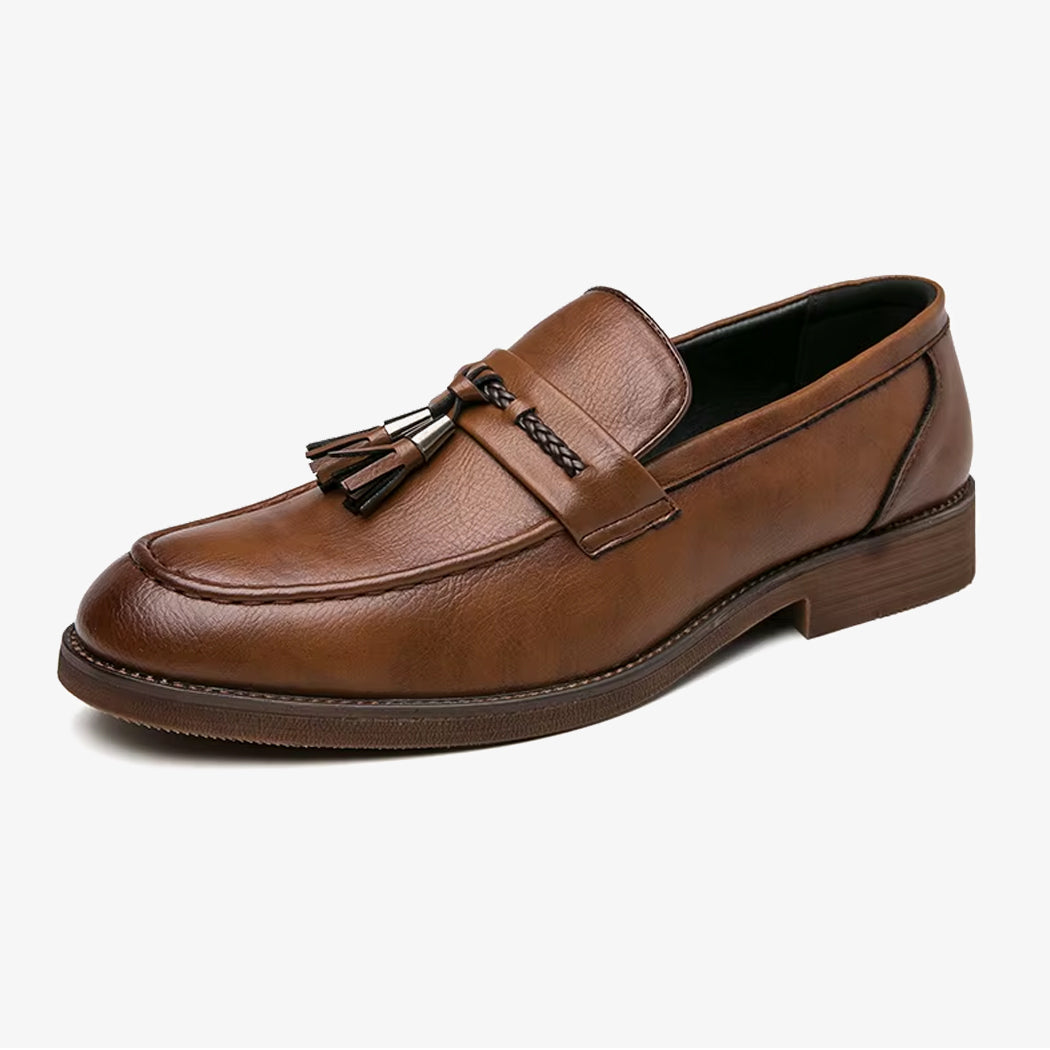 Een elegante bruine herenloafer van leer met kwast op een witte achtergrond