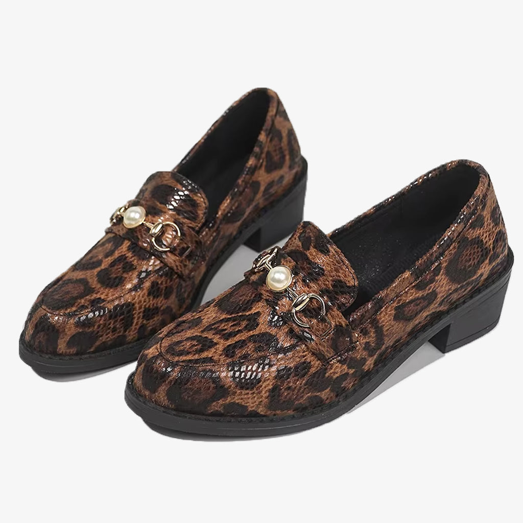 Paar luipaardloafers met slangeneffect en pareldetail op een witte achtergrond