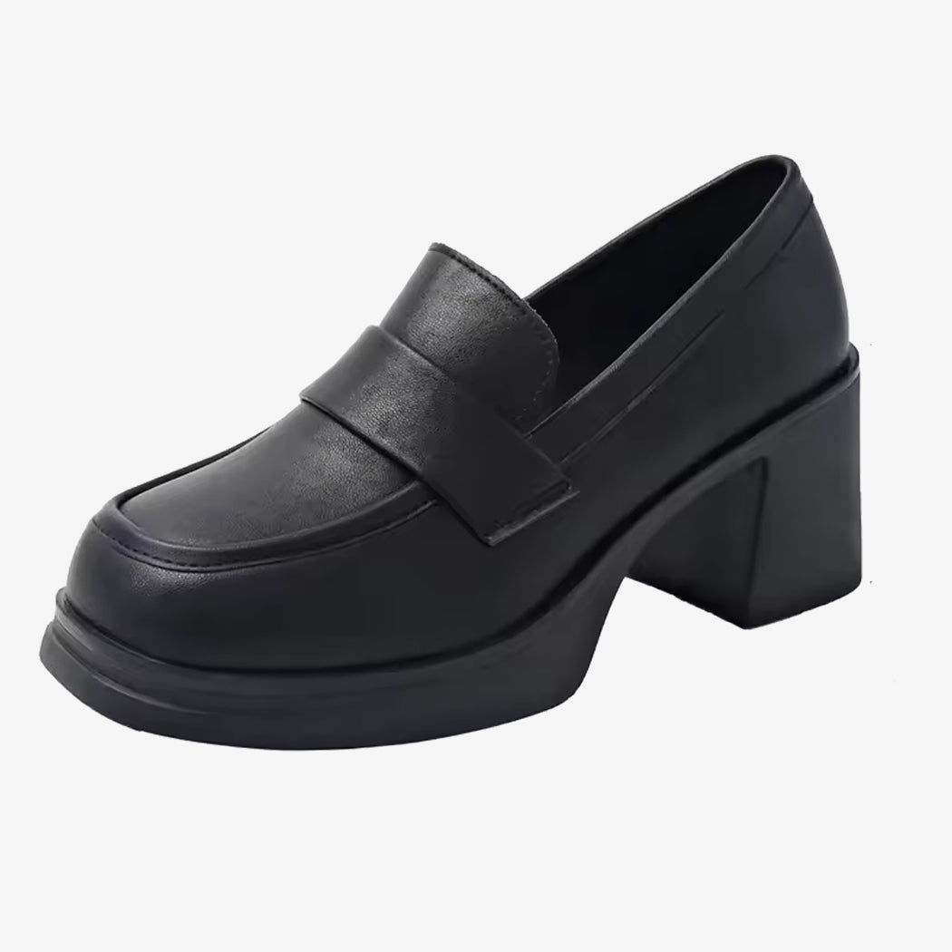 Een paar loafers met hak van synthetisch leer voor dames in zwart op een witte achtergrond.