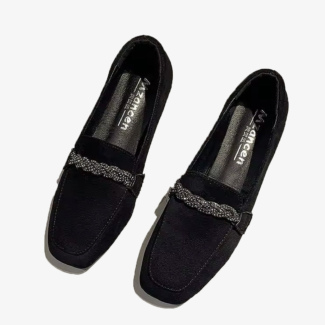 Zwarte suède loafers met strass-ketting op een witte achtergrond