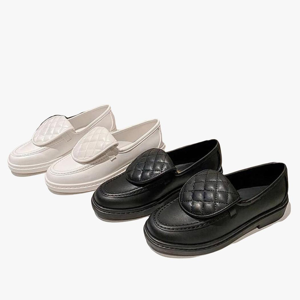 je ziet twee paar loafers met gewatteerd bovenstuk en blokhak voor dames, een wit paar en een zwart paar naast elkaar