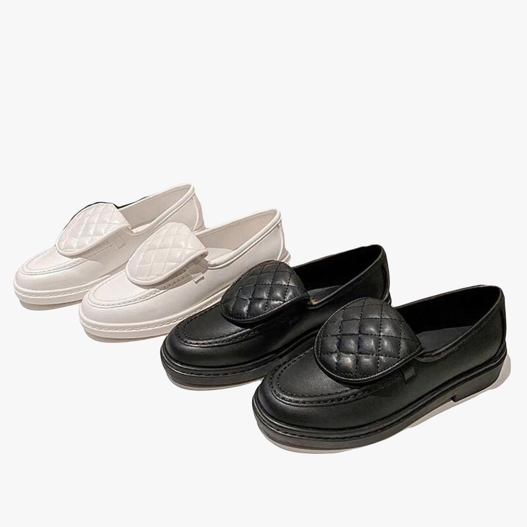 je ziet twee paar loafers met gewatteerd bovenstuk en blokhak voor dames, een wit paar en een zwart paar naast elkaar