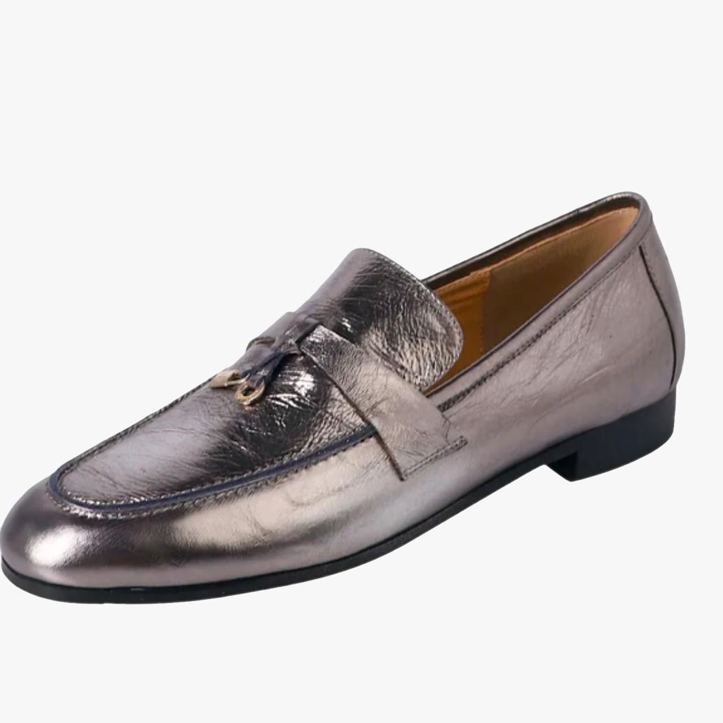 je ziet op een witte achtergrond een zilverkleurige dames loafer met kwastjes van echt leer