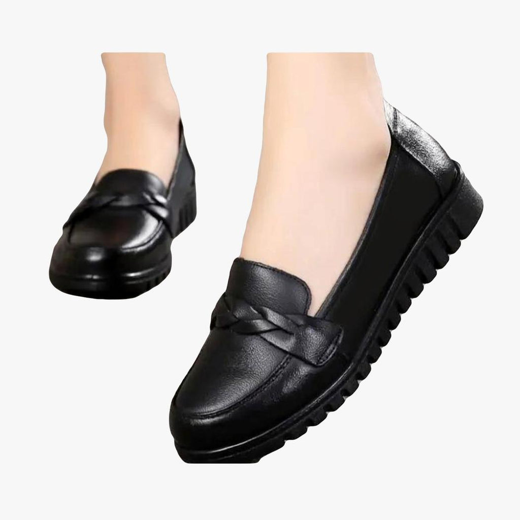 je ziet een paar zwarte loafers gedragen door een vrouw, alleen haar voeten zijn zichtbaar
