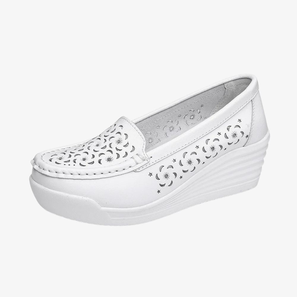 Een witte loafer in profiel, met een sleehakzool en gaten aan de voor- en zijkanten.