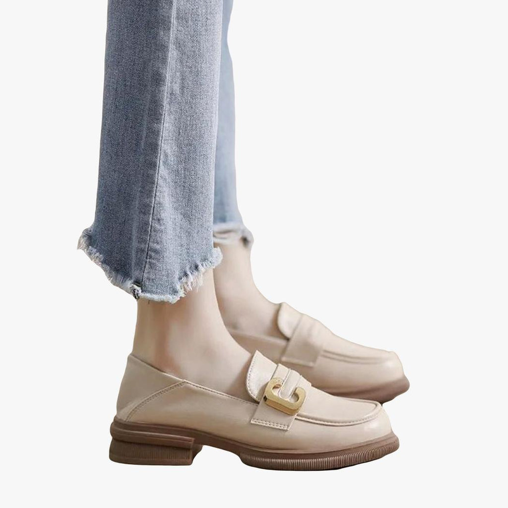 de voeten van een vrouw in een jeans zijn te zien, ze draagt zachte beige loafers van synthetisch leer