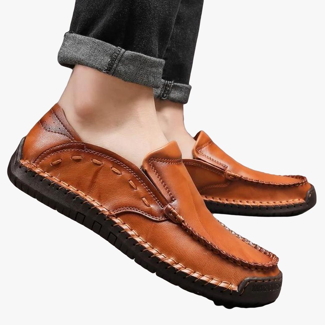 je ziet de voeten van een man die zachte loafers van synthetisch leer in de kleur kameel draagt