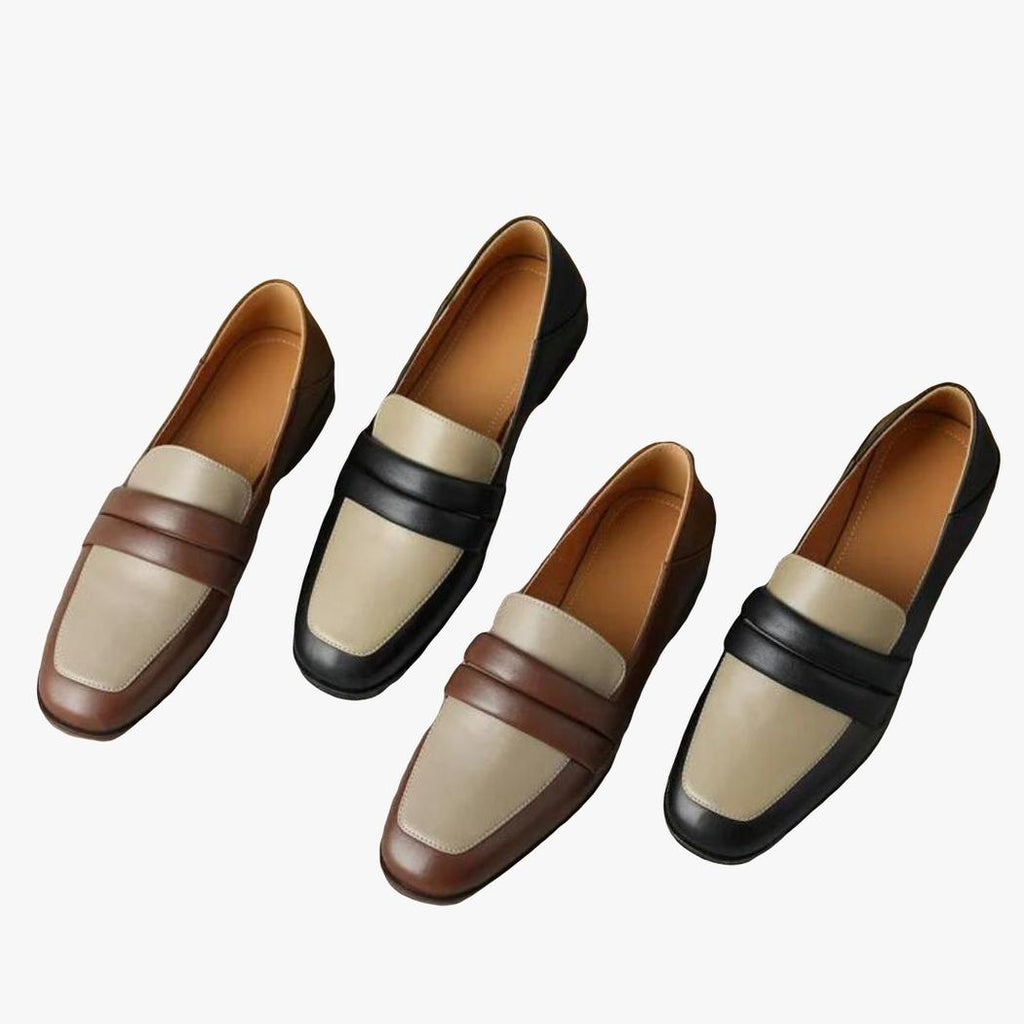 Op een grijs en bruin oppervlak zie je twee paar tweekleurige loafers met vierkante hakken in bruin en zwart voor dames, van echt leer