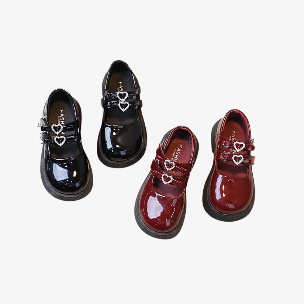 2 paar meisjesloafers, in zwart en bordeaux, met een glanzende uitstraling en twee bandjes met daarop twee hartjes van strass.