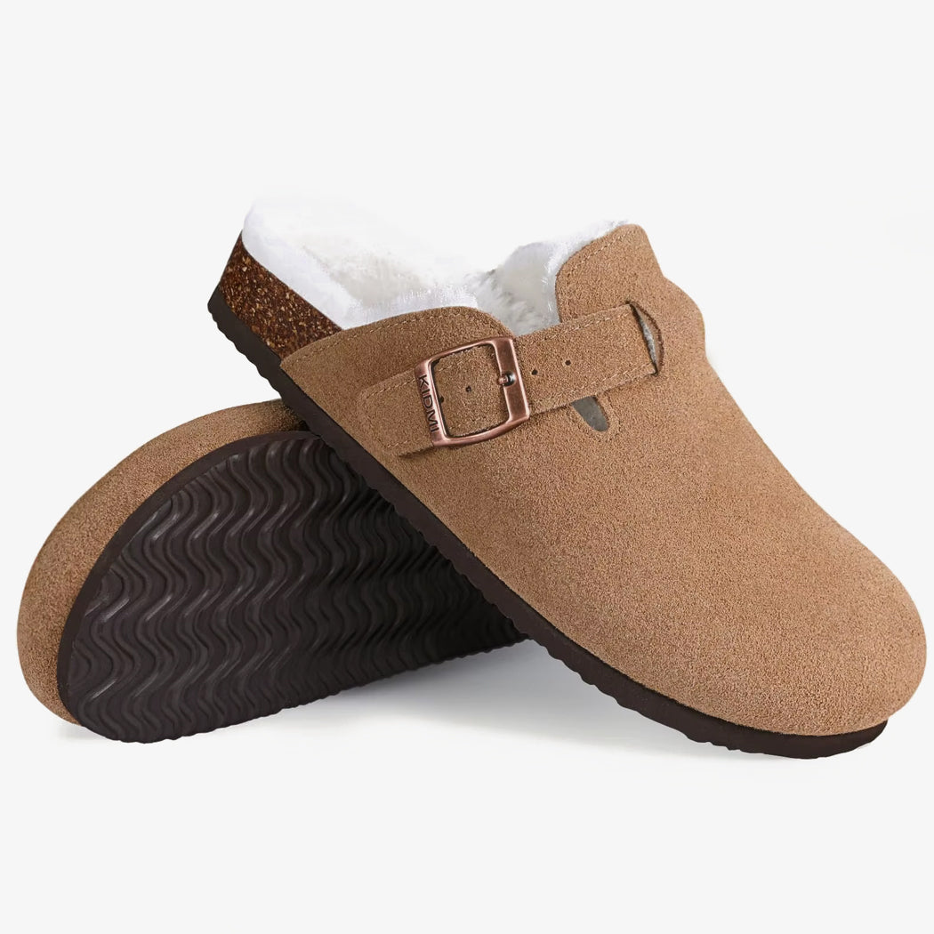 Paar loafers in clogs-stijl van bruin suède met voering, op elkaar gestapeld tegen een witte achtergrond