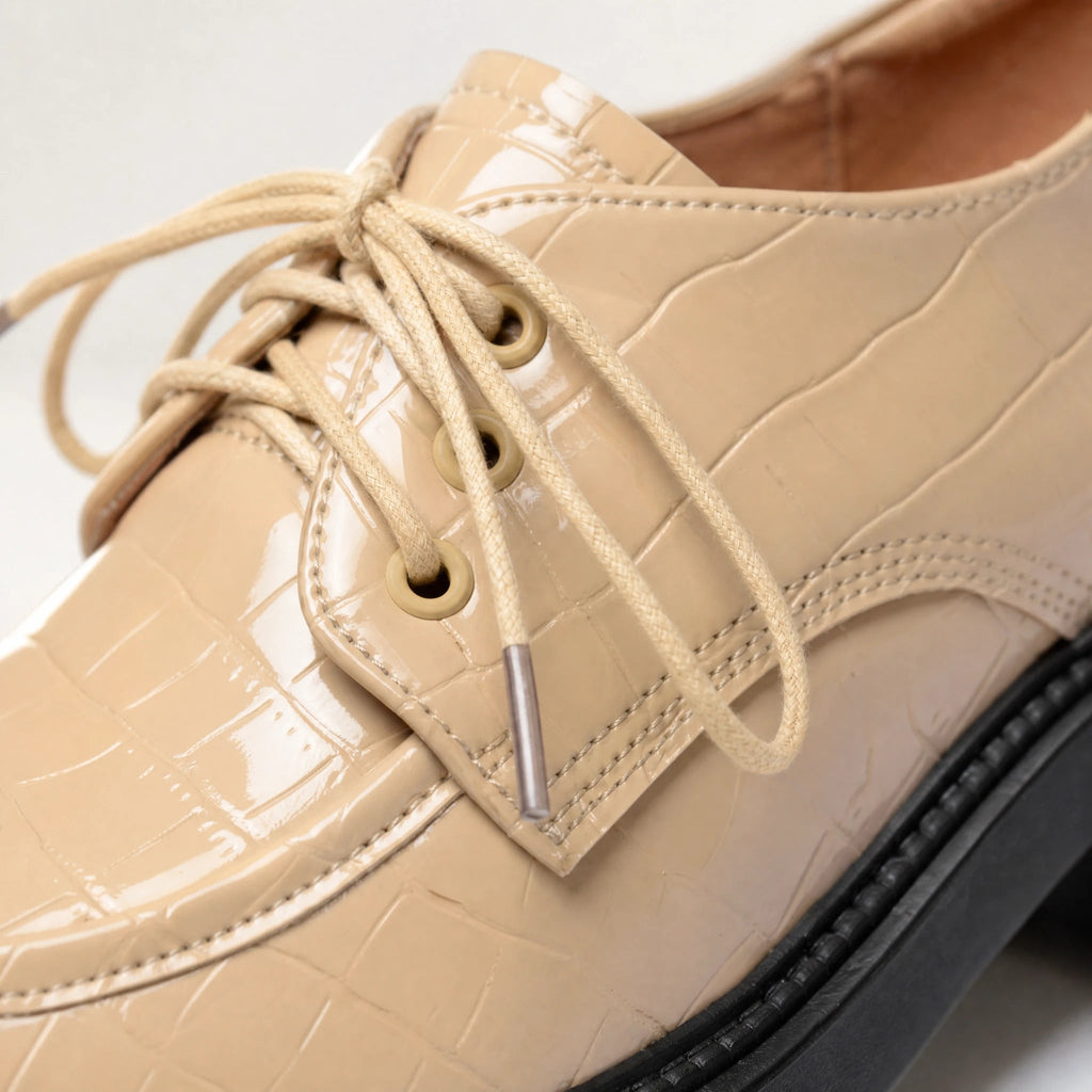 Beige lakmocassin met zwarte geprofileerde zool