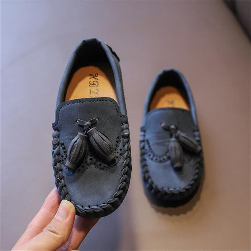 Elegante loafers met kwastjes voor jongens met een beige achtergrond
