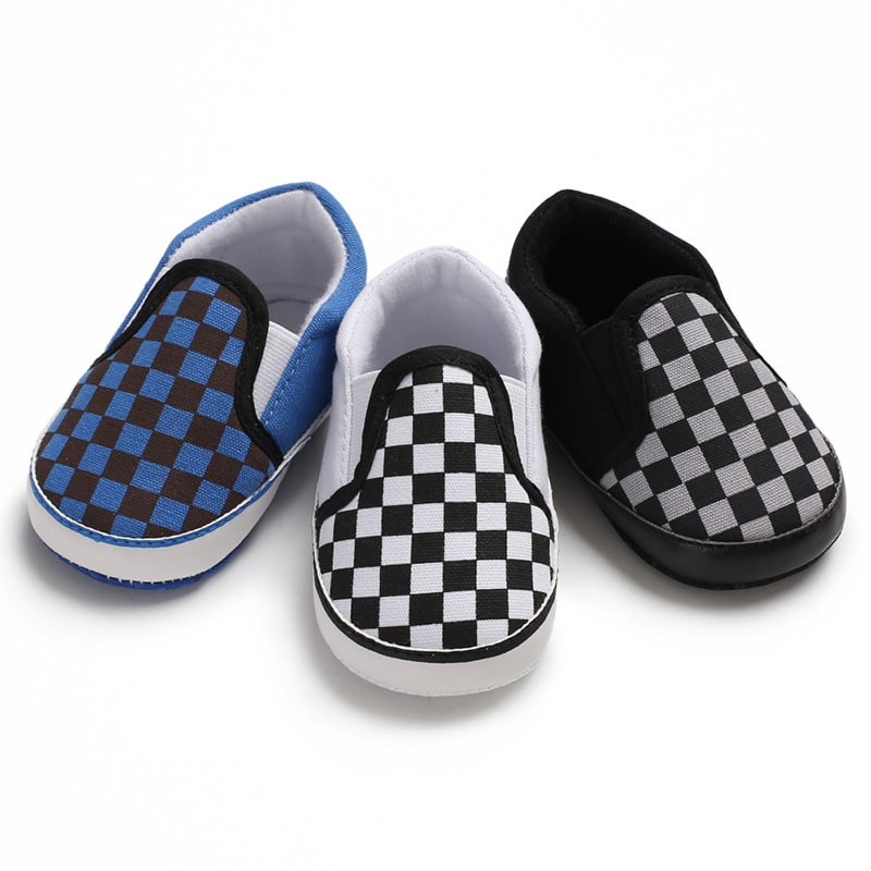 Op een witte achtergrond, 3 modellen baby mocassins in zwart en blauwe dambordstof, zwart en wit en grijs en zwart