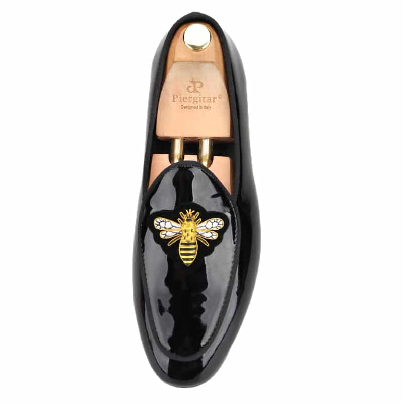 Glimmende loafers met gouden vlindergesp op een witte achtergrond