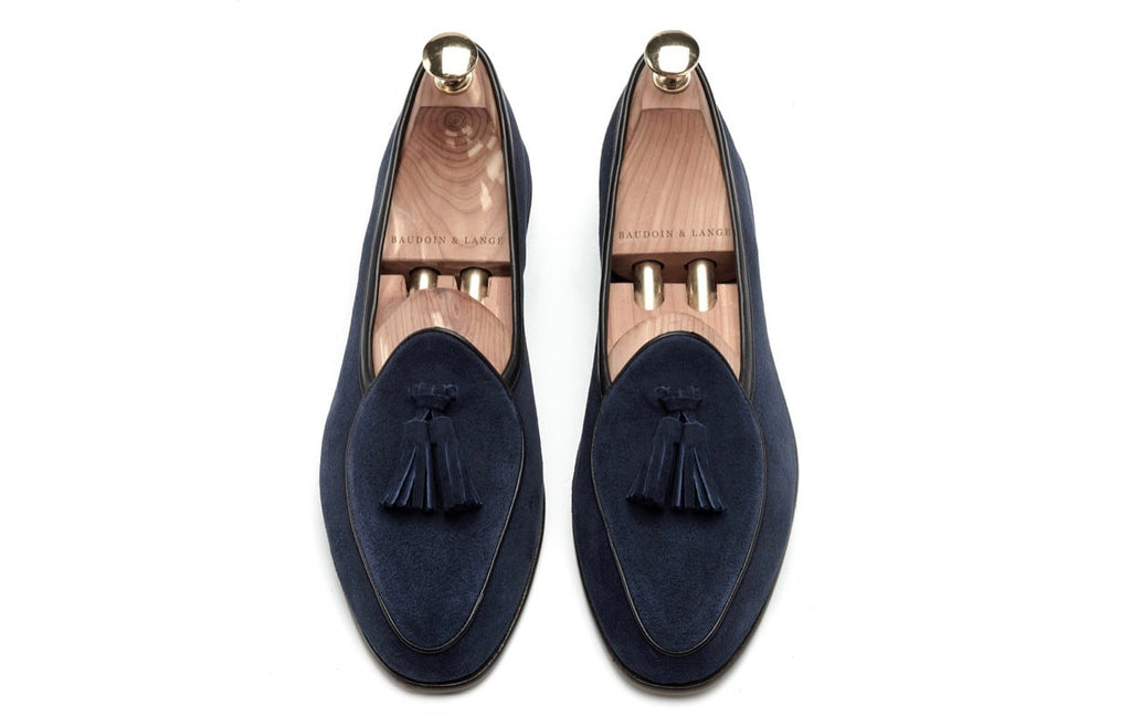Paar marineblauwe suède loafers op een witte achtergrond