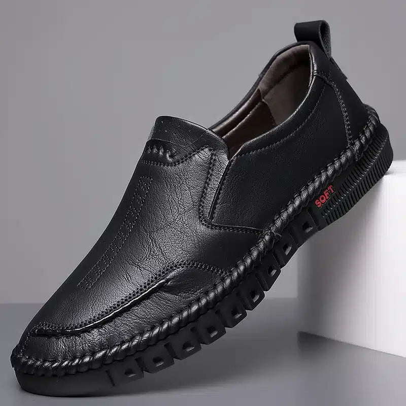 Zwarte mocassin op een witte ondergrond, grijze achtergrond.