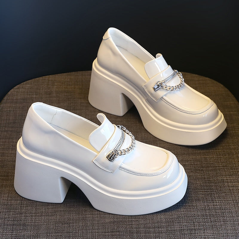 witte lakleren loafer met offset hak op een bruine tafel