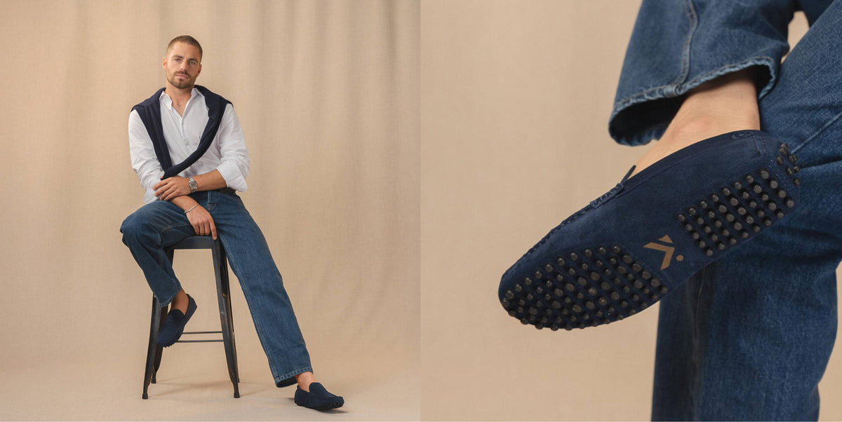 Man op een kruk met marineblauwe suede loafers, met detail van de noppenzool