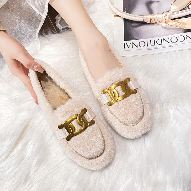 mocassin van imitatiebont met kwastje bovenop, gedragen door een vrouw op een vloerkleed van fleece