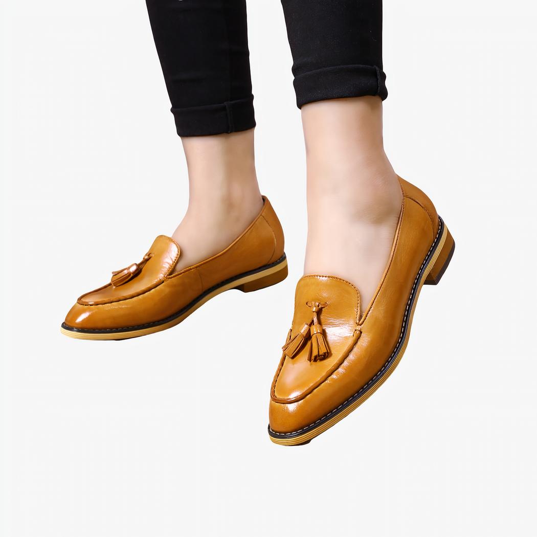 Vrouw in een zwarte broek en kameelkleurige leren loafers