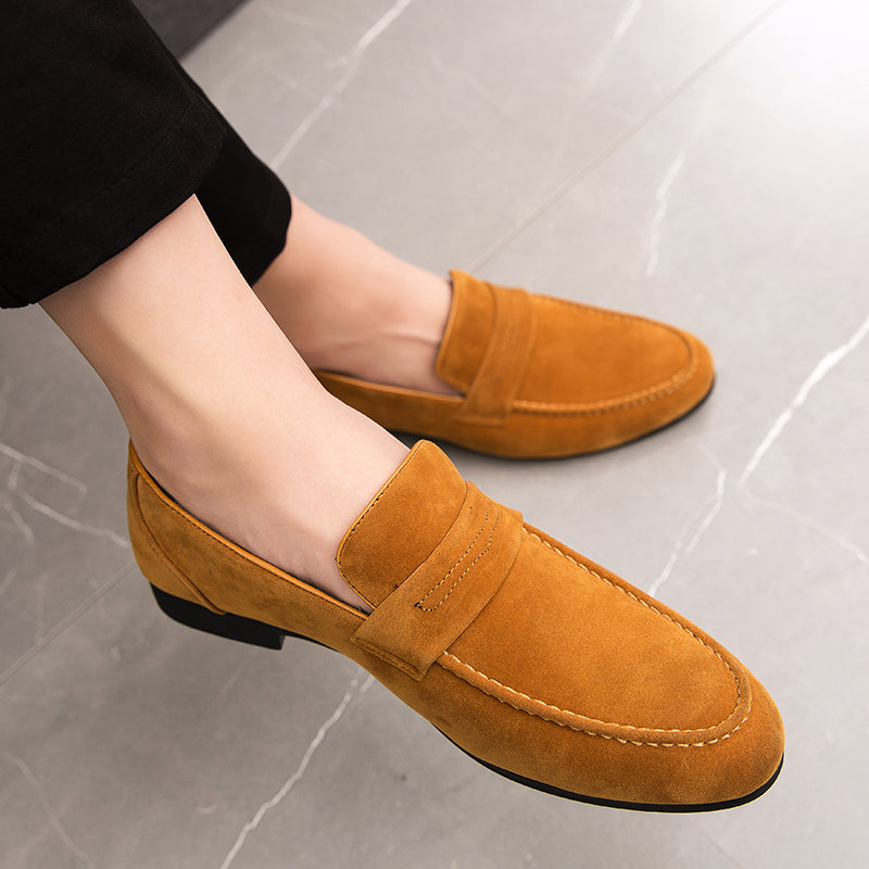 bruine loafers gedragen door een man met gekruiste benen en zwarte broek
