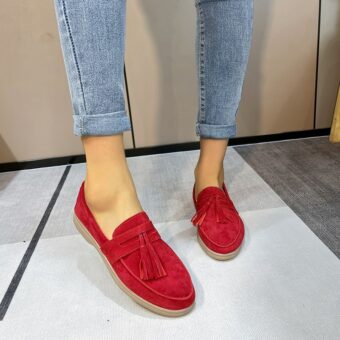 Vrouw draagt rode leren loafer met kwastje