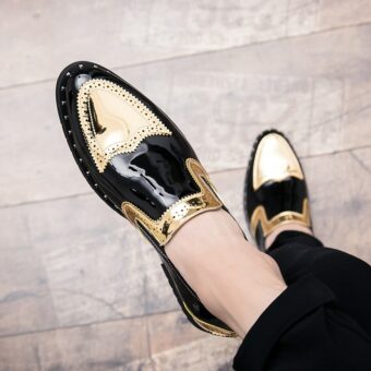 Gekruiste voeten in zwarte en gouden lakschoenen op een parketvloer
