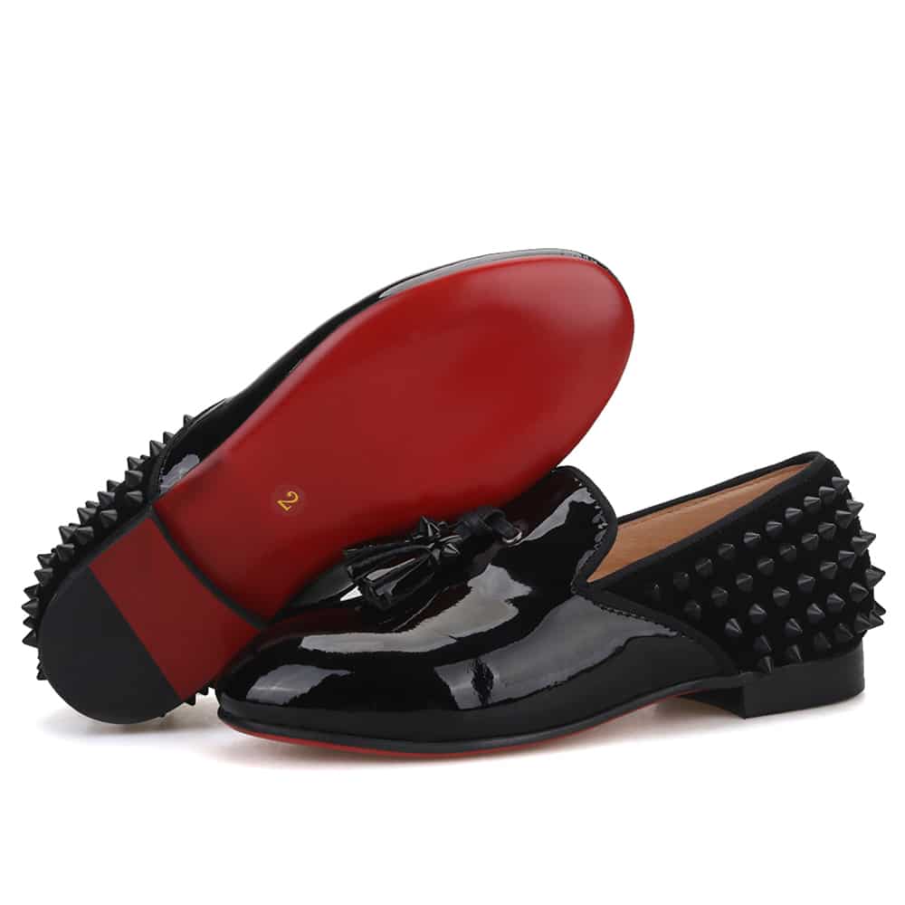 Zwarte lak loafers met spikes aan de achterkant van de schoen.
