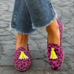 Vrouw in kleermakerszit op straat met jeans en roze kwastjes met luipaardprint