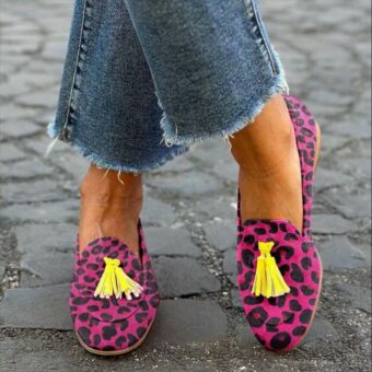 Vrouw in kleermakerszit op straat met jeans en roze kwastjes met luipaardprint