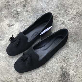 Paar zwarte suède-effect loafers op een grijze betonnen vloer