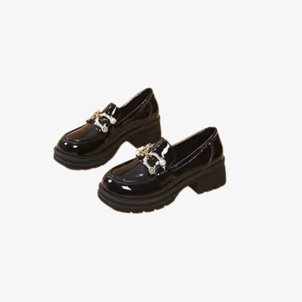 Mocassins noirs vernis pour femme, au style chic et moderne. Dotés de talons épais pour une allure et une bonne stabilité, ils sont ornés d'une boucle métallique argentée élégante sur le dessus, ajoutant une touche raffinée à leur design brillant.