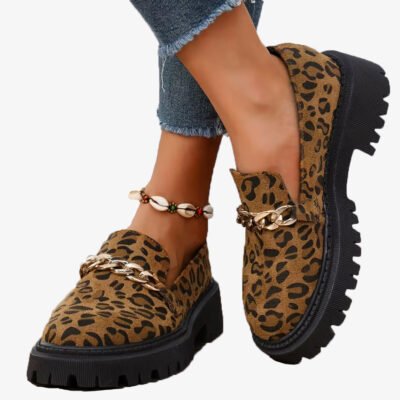 Paar loafers van luipaardsuède met plateauzool en ketting, gedragen met een jeans en een enkelbandje van schelpen