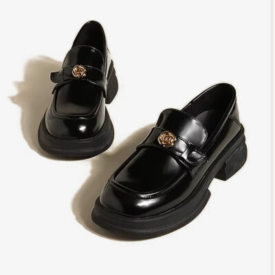 Zwarte plateauschoenen met metalen bloemendetail op een witte achtergrond