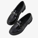 Zwarte gelakte loafers met metallic detail op een witte achtergrond